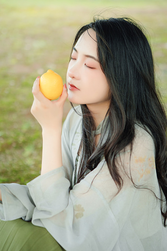 Focused European female picking ripe organic mandarins in plastic container box in orchard or on farm