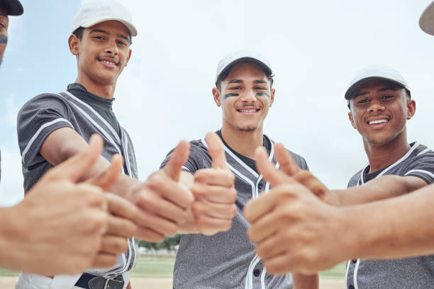 beisebol, homens de esportes e polegares para cima sucesso na motivação de exercícios de fitness, confiança de treinamento e apoio da comunidade de exercícios. equipe, amigos e sorriso com gols de vencedor ou sinal de mão alvo no campo esportivo - baseball cap men ok thumbs up - fotografias e filmes do acervo