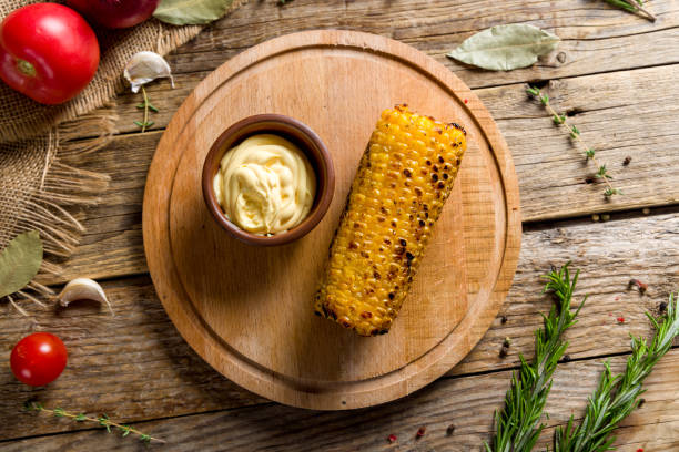 istock Baked corn on a board with cheese sauce on wooden table top view 1446946453