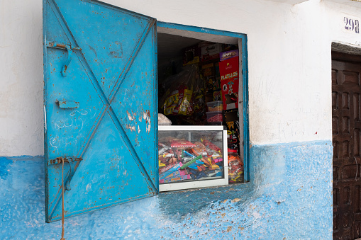 Tetouan, Morocco - April 19, 2019: Kiosk with a small candy counter installed in a window with a blue metal door.