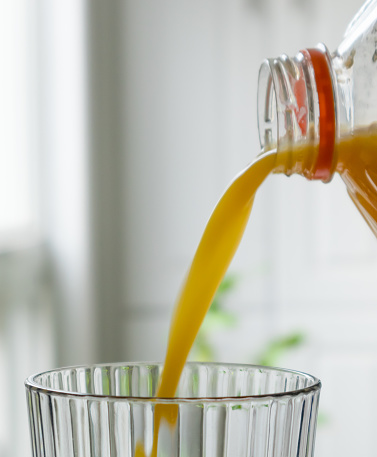 Pouring orange juice into glass from a plastic container