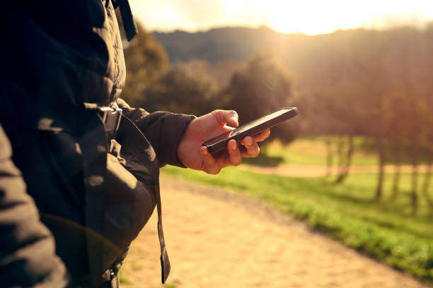istock Sunset, hand or man with phone while hiking countryside with 5g network, networking or social media outdoor. Lens flare, fitness or sport male with smartphone for location search or social network 1446948904