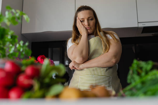피곤하고 슬프고 지루한 플러스 사이즈 금발 여자는 머리를 잡고 무엇을 요리해야할지 생각하지 않습니다. 레시피를 찾고 - mature adult sadness overweight women 뉴스 사진 이미지