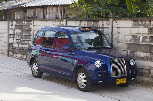 Blue retro styled british taxi is parked in Bangkok in small street in residential district of Bangkok Ramintra