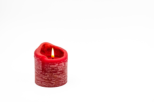 Greeting card on white background with burning red candle for Christmas and Adent as studio shot