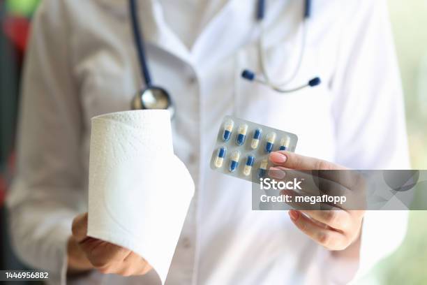 Female Doctor Holding Blister Of Pills And Toilet Roll Stock Photo - Download Image Now