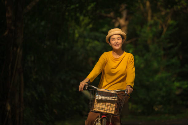 주말에 공원에서 자전거를 타는 웃는 여자 간단한 즐거움 - mental health women asian ethnicity bicycle 뉴스 사진 이미지