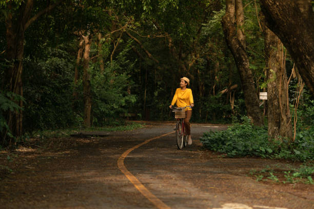 femme, faire du vélo dans le parc - mental health women asian ethnicity bicycle photos et images de collection