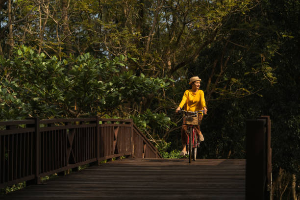 femme, faire du vélo dans le parc - mental health women asian ethnicity bicycle photos et images de collection