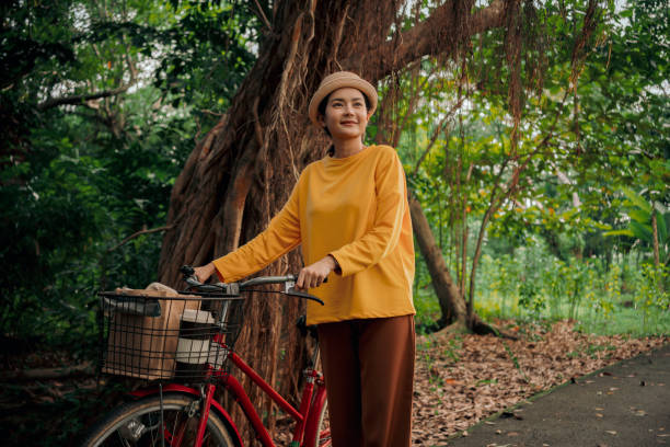 주말에 공원에서 자전거를 타는 웃는 여자 간단한 즐거움 - mental health women asian ethnicity bicycle 뉴스 사진 이미지