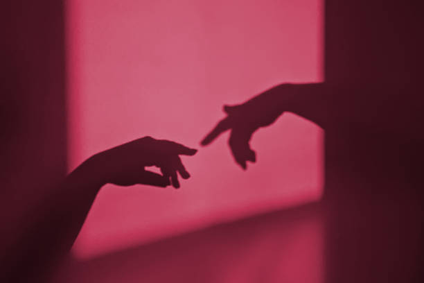istock Abstract shadow silhouette of gesture touch by humans palms from sunbeam on wall. Image toned in color of the year 2023 viva magenta 1446957594