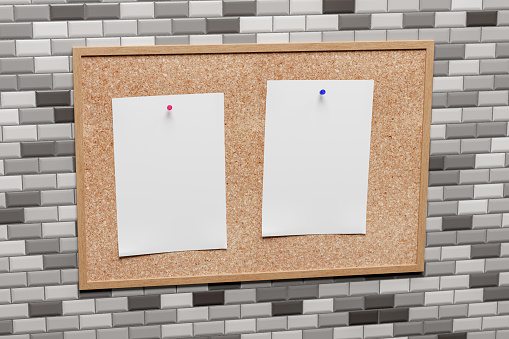 Notice board with blank paper copy space sheets pinned to cork board. On tiled wall.