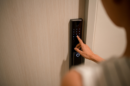 Over the shoulder view : Woman Pressing down a password on electronic access control to unlock a door room at home