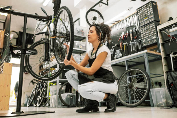 Young female bicycle mechanic working on a bicycle Beautiful young female bicycle mechanic working on a customer bicycle bicycle shop stock pictures, royalty-free photos & images