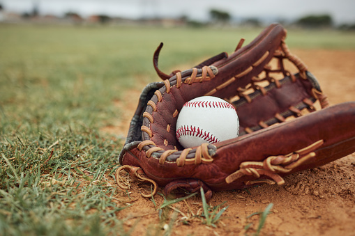 Baseball, ball and glove on an outdoor pitch for sport training, fitness or a tournament game. Exercise, sports equipment and softball match on a professional field or stadium with grass and sand.