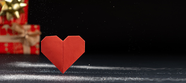 Banner for Valentine's Day, red paper heart and gifts on a black background, origami, place for text