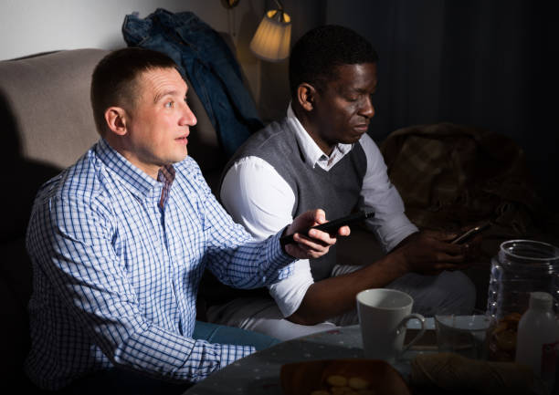 istock African man with phone while friend watching tv 1446968140