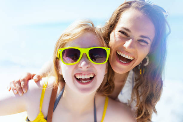 istock smiling stylish mother and child at beach having fun time 1446968751