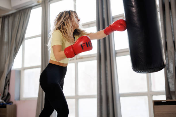 istock Young female boxer training with punching bag in the gym 1446968886