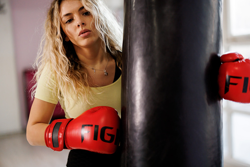 Young boxing woman standing by punching bag ready for training