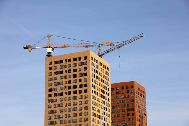 青い空の背景にタワークレーンと未完成の建物。市内の住宅建設、アパートブロック - crane nobody color image photography ストックフォトと画像