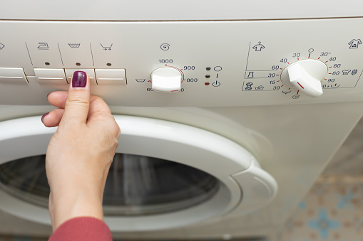 a person chooses a washing mode with a switch. washing mode. temperature mode. washing machine. High quality photo
