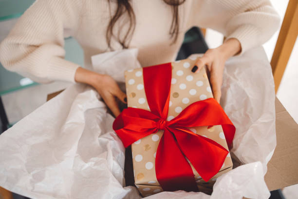 istock A woman unwrapping a Christmas present she received 1446980291