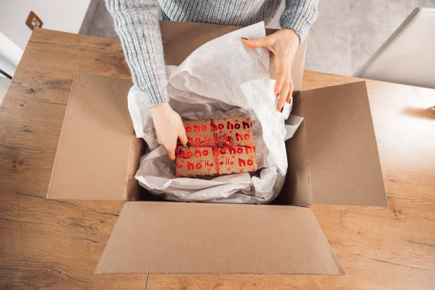 istock A woman wraps a Christmas present in a cardboard box 1446980325