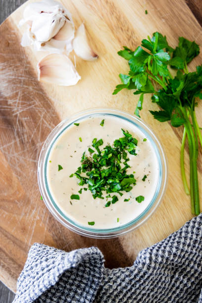 Ranch Dressing Vegan white ranch dressing in a glass bowl on a wooden cutting board. Decorated with fresh parsley and garlic and grey napkin. ranch dressing stock pictures, royalty-free photos & images