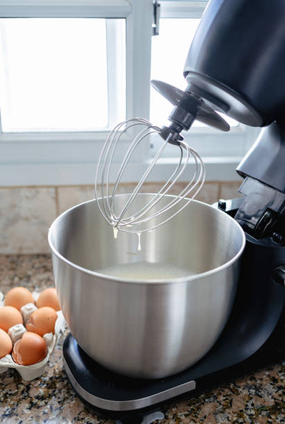 istock Mixer bowl with cake preparation inside and some eggs on the side. Close up caption. 1446986178