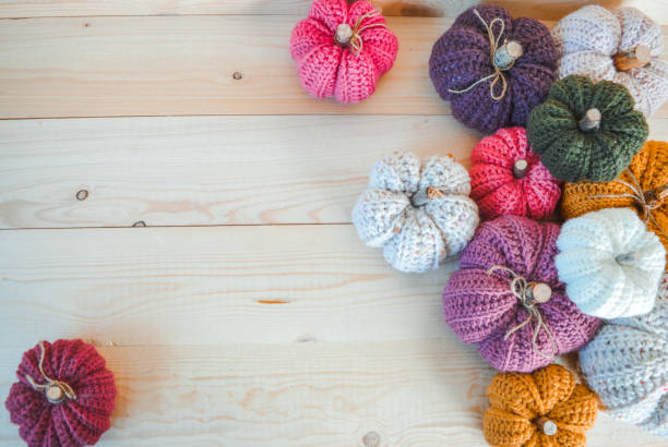 Multi colored balls of yarn and crochet hooks on white wooden background