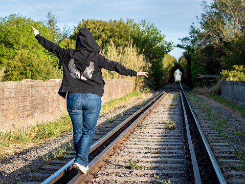 Woman walking on the train tracks. Liberty sensation. Young man walking happily on the train tracks. woman walking away