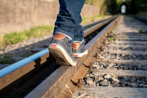 Person walking on the train tracks. Feet of person on the train tracks. Person walking following the train tracks. Mode of transportation. concept photo