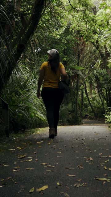 Brown hair woman admiring the beauty of nature while walking among pathway in the middle of rainforest