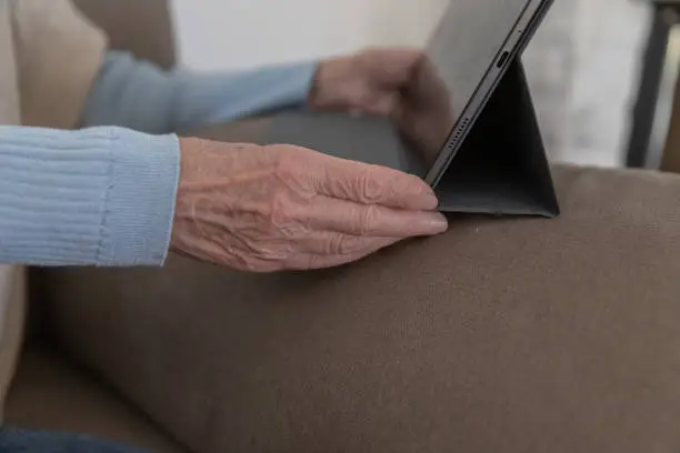 Old hand holding a tablet