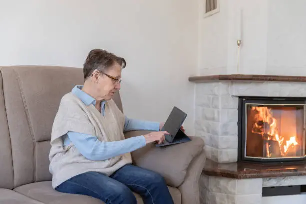 Old woman alone with tablet in living room