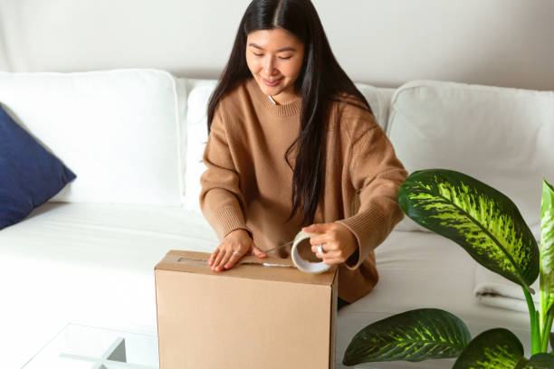 istock Young woman unpacking or packing the package with present 1446993460