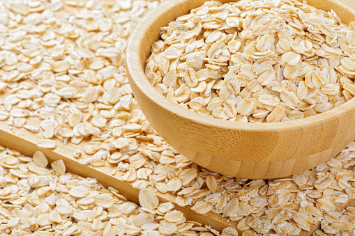 Rolled oats or oat flakes on stone background.