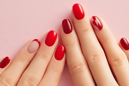 Set of nicely manicured  female fingernails painted in red over white background.Adullt caucasian woman,her hands forming letter X.Shot from above.