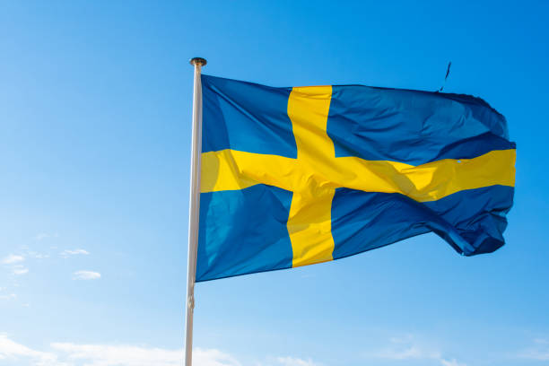 istock Swedish flag waving against blue sky 1447003242