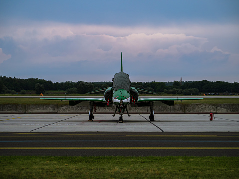 Modern green-white saudi military training jet parking at an airfield after mission, frontal view, cloudy sunset behind, Kecskemet airshow Hungary 2021