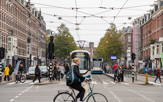 Amsterdam, Netherlands - October 15, 2022: A picture of an intersection in Amsterdam showing bike, tram, car and pedestrian traffic.