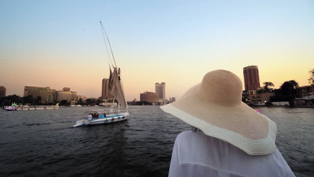 Tourist women with straw hat on cruise boat on Nile River, enjoying the skyline of Cairo, Egypt. Travling and vacation in Egypt