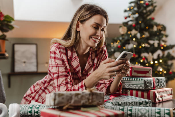 istock Lovely woman using smart phone during Christmas time at home 1447017585
