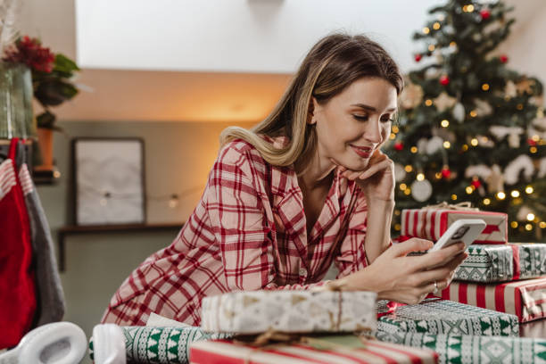 istock Lovely woman using smart phone during Christmas time at home 1447017587