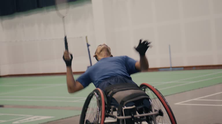 Asian disabled badminton player in wheelchair playing badminton with friends.