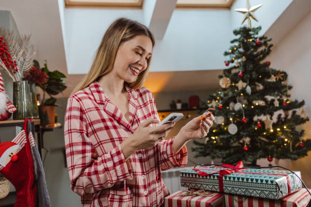 istock Lovely woman using smart phone for e-commerce during Christmas time 1447017738