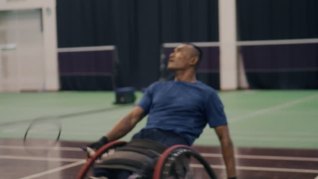 Asian disabled badminton player in wheelchair playing badminton with friends.