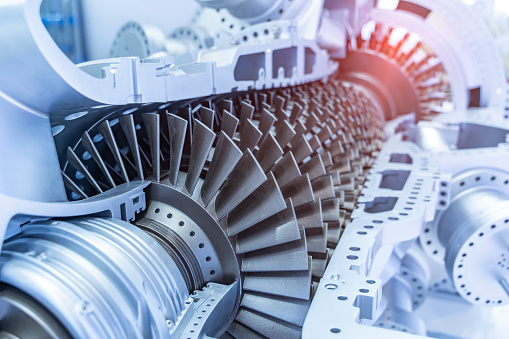 A large white jet engine turbine, with a lot of silver blades interconnected to each other and a central silver dome, in the middle of the jet turbine.  It is not connected to any plane, and the background is plain white.