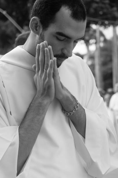 a young priest prays during the corpus christ procession - confessional nun catholic imagens e fotografias de stock